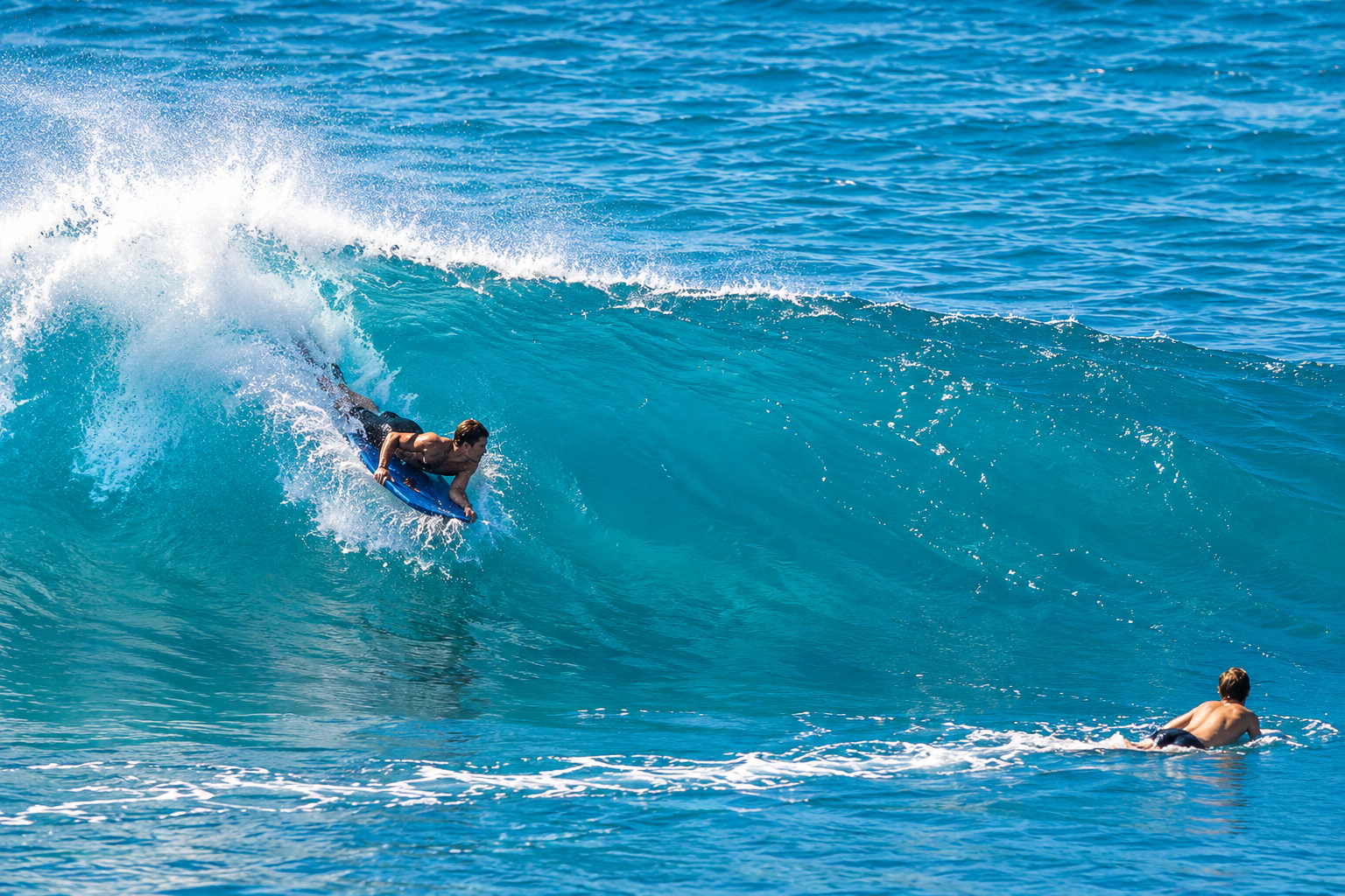 Bodyboarder riding a turquoise ocean wave